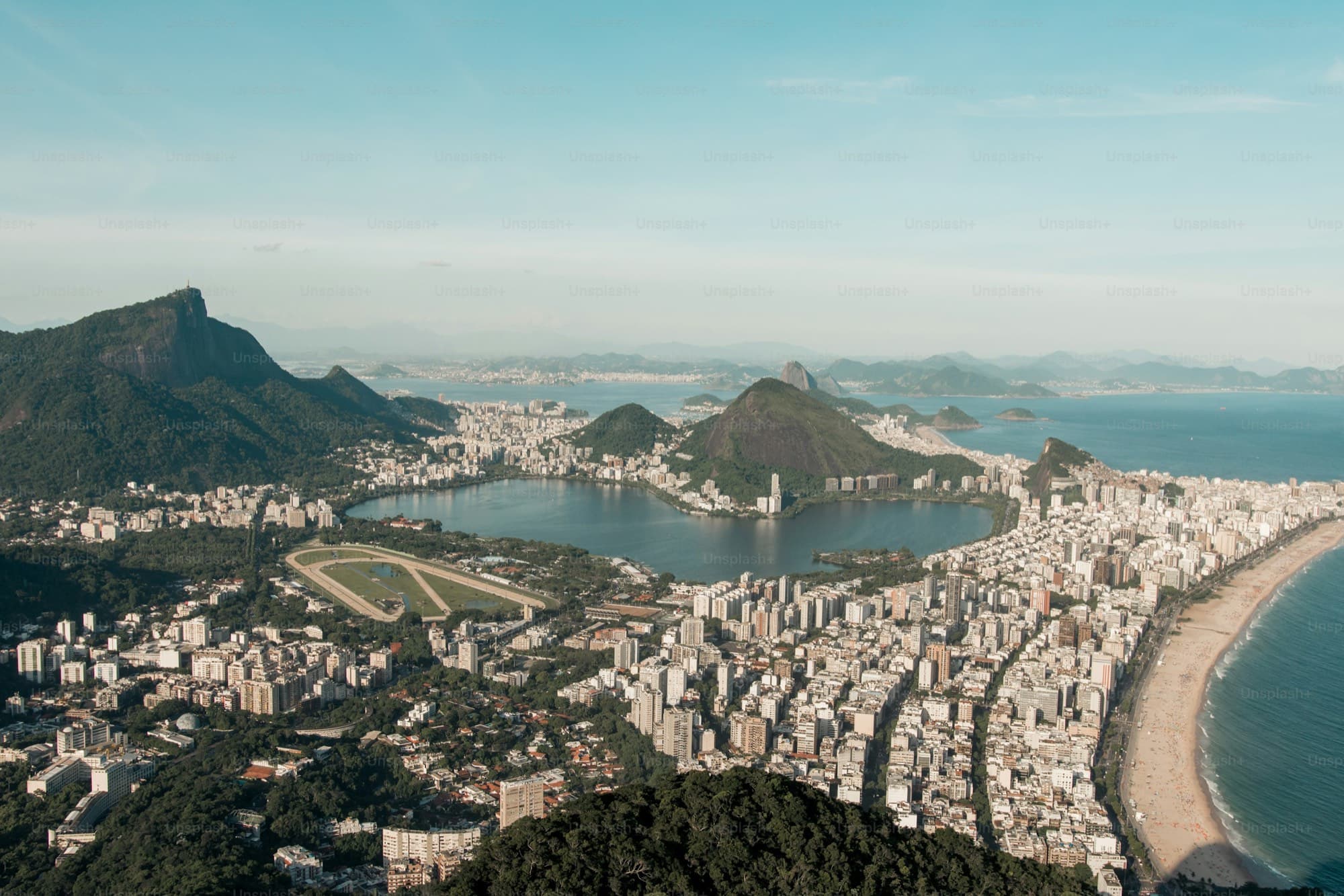 A beach city between a lagoon and green hills seen from above, with the ocean beyond